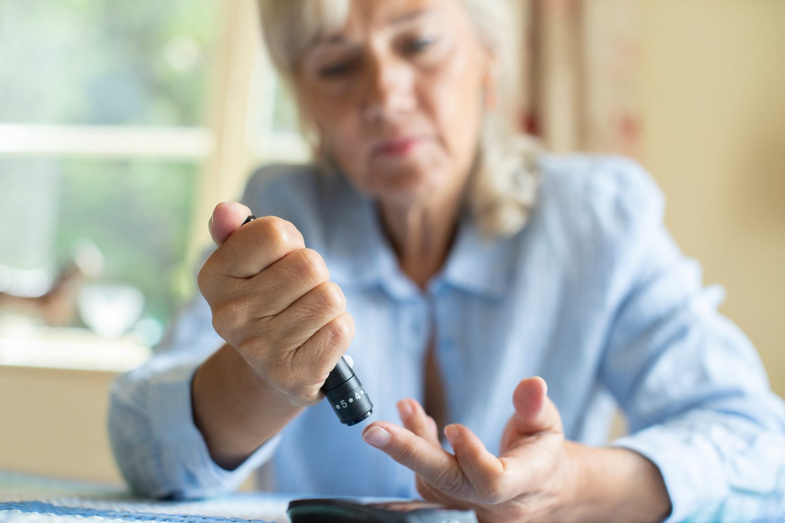 A woman checking her blood sugar at the kitchen table