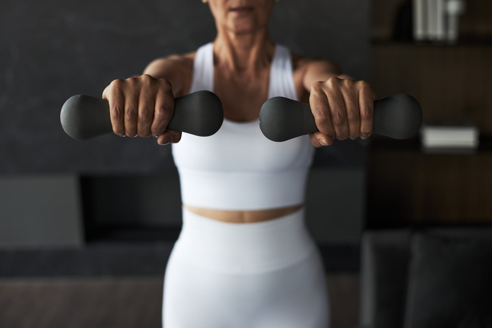 A woman holding light dumbbells during a strength session at home